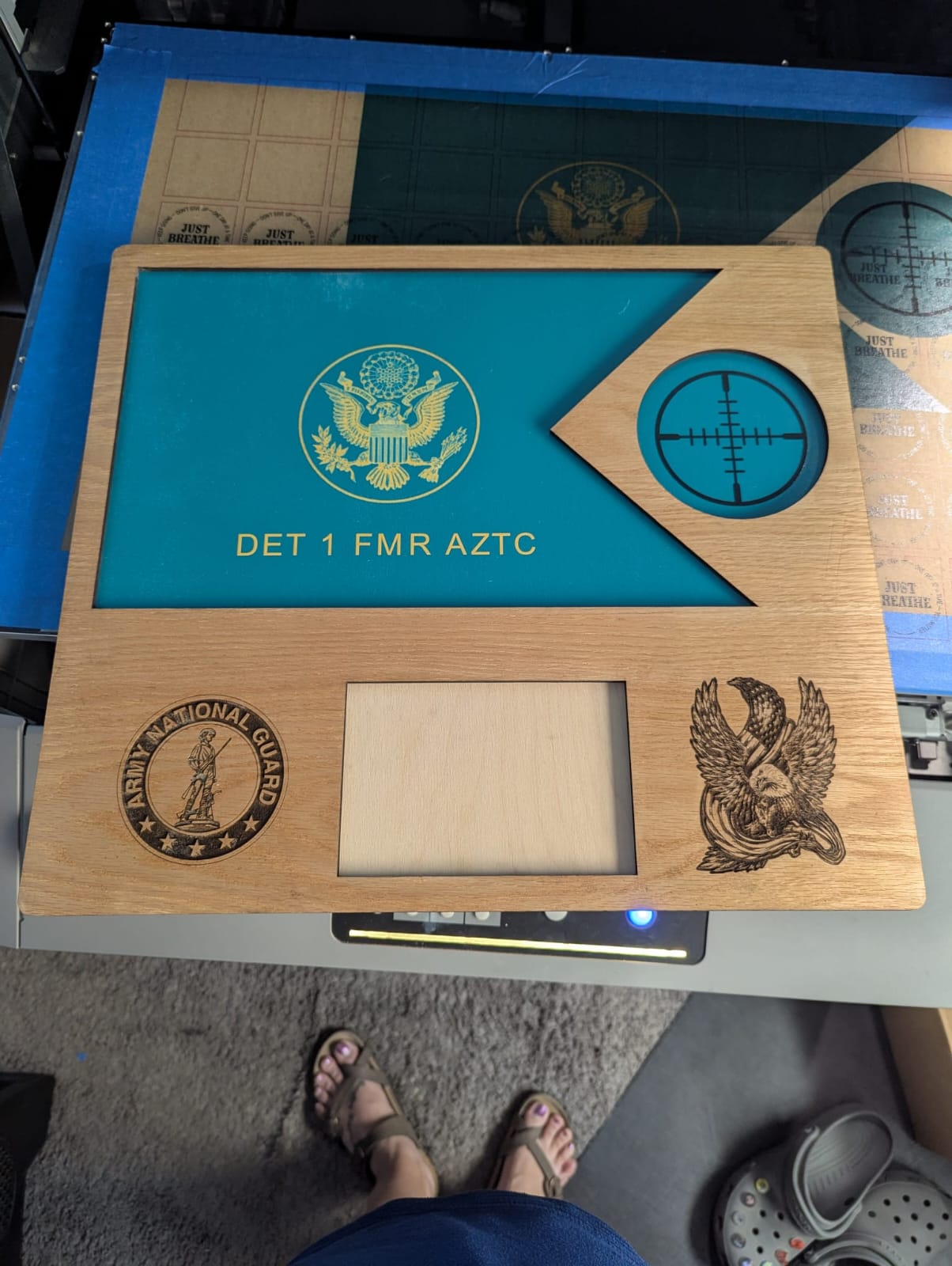 Wooden plaque with engraved designs and text on a blue surface